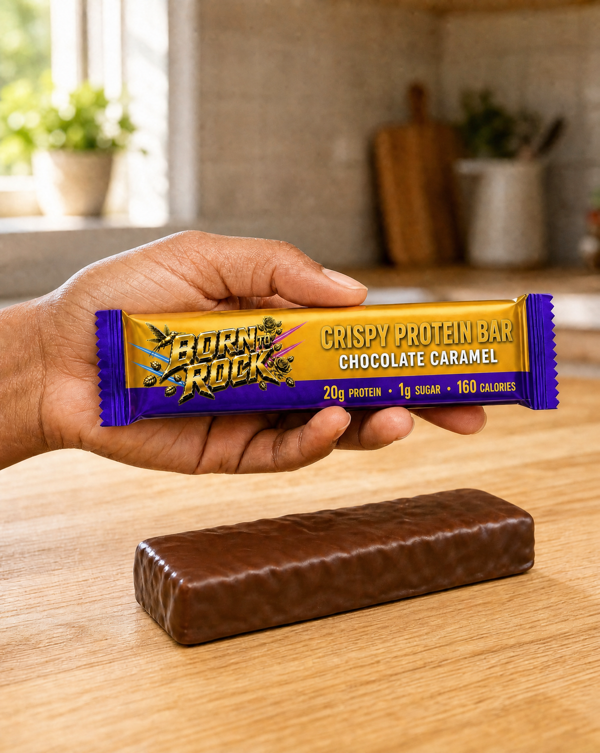 Born To Rock crispy chocolate caramel bar wrapper held in one hand beside the unwrapped bar