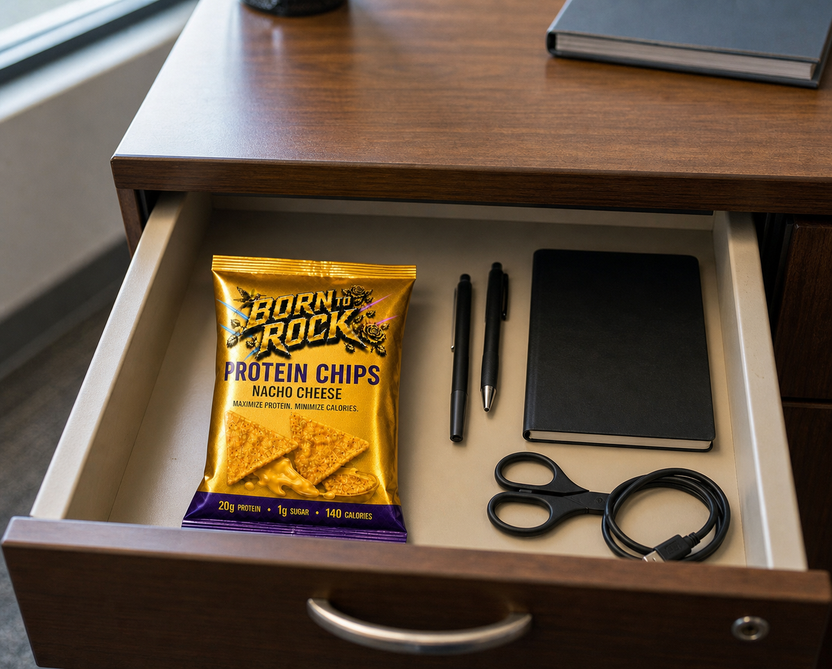 The bag lying flat in an open office desk drawer beside pens, a notebook and a cable, showing how compact it is