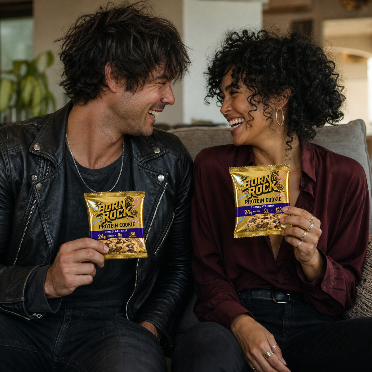 Two friends laughing on a couch with Born To Rock Protein Cookies