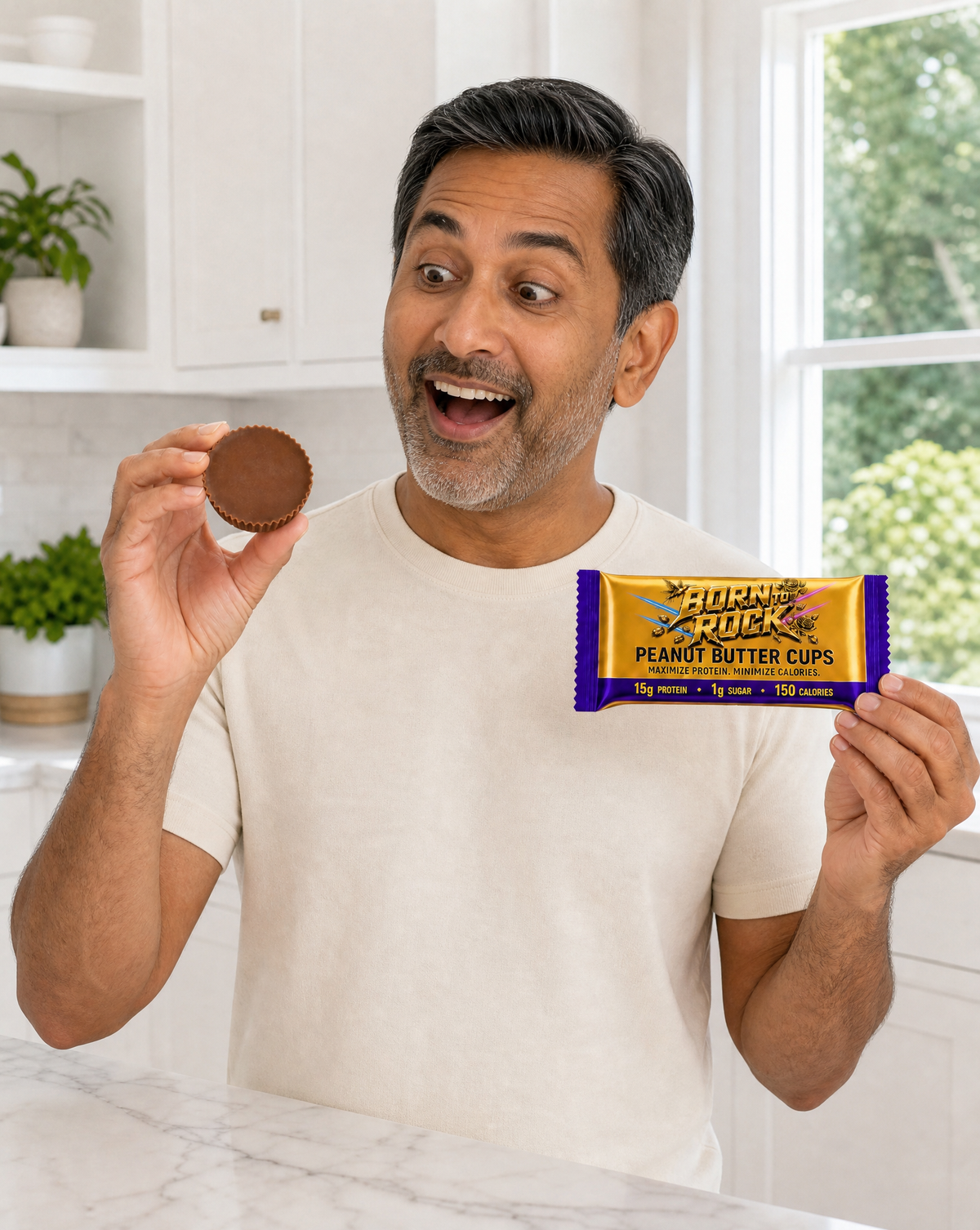 A man in a bright kitchen doing a delighted double take, holding up the wrapped pack in one hand and a peanut butter cup in the other